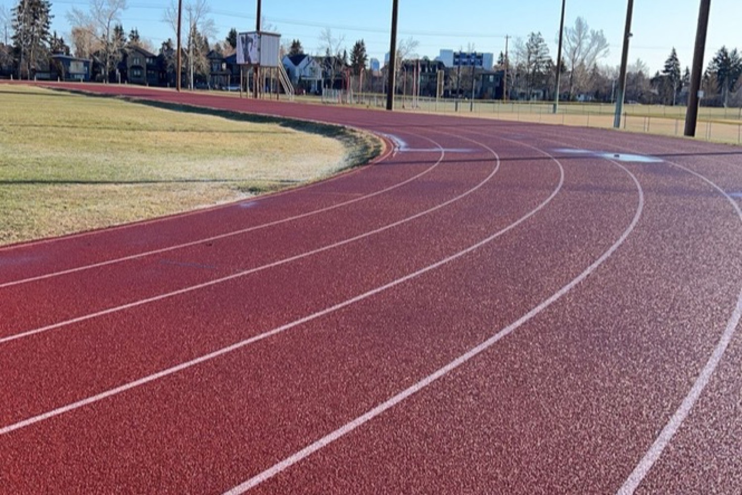 An empty running track curving into the distance under a clear sky
